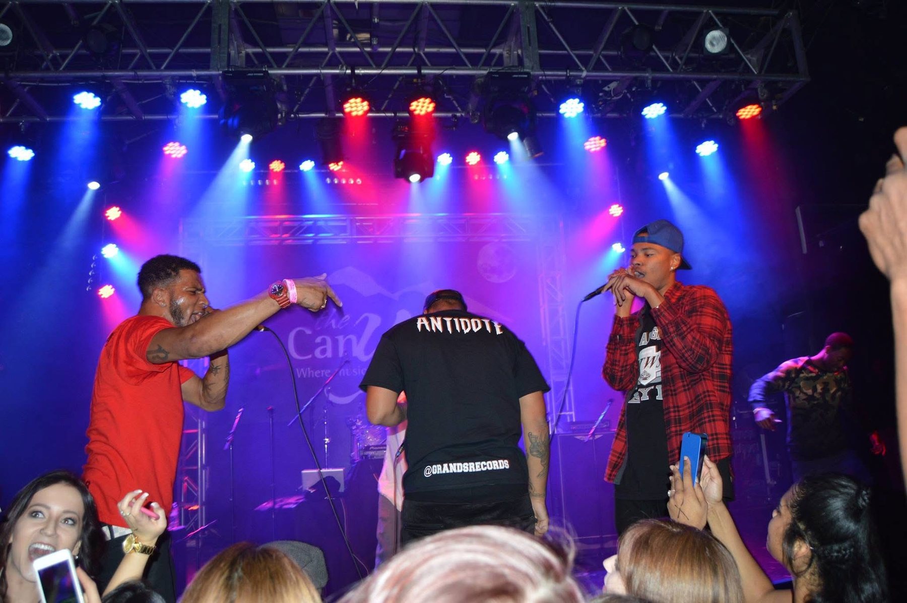 Antidote performing live at The Canyon under full stage lights, ANTIDOTE across the back of the shirt, crowd filming